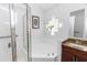 Bright bathroom featuring a corner tub, glass block window, and vanity with granite countertop at 13624 Springtide Ct, Orlando, FL 32826