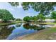 Serene pond reflects the natural beauty of the surrounding trees and clear blue sky at 13624 Springtide Ct, Orlando, FL 32826