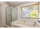 Bathroom featuring a tub, shower, and window overlooking lush foliage at 212 Hound Run Pl, Casselberry, FL 32707