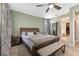 Bedroom with a king bed, bench, ensuite bathroom, and light green walls, creating a serene atmosphere at 5981 Sierra Crown St, Mount Dora, FL 32757