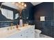 Stunning bathroom with navy tiled walls, dual sinks, and glamorous gold mirrors at 690 Cascading Creek Ln, Winter Garden, FL 34787