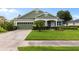 Charming single-story home featuring a well-manicured lawn, lush landscaping, and a welcoming front porch at 690 Cascading Creek Ln, Winter Garden, FL 34787
