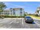 View of the condo building with gray paint, well-manicured hedges, and parking spaces at 13839 Fairway Island Dr # 1128, Orlando, FL 32837