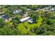 Aerial view showcasing the home, outbuilding, metal roof, green lawns, mature trees, and neighborhood at 1405 Pioneer Trl, New Smyrna Beach, FL 32168