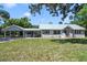 Charming single-story home with a light metal roof, well-manicured lawn, and covered parking at 1405 Pioneer Trl, New Smyrna Beach, FL 32168