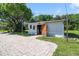 Outbuilding featuring an open doorway and an expansive paver parking area near the manicured yard at 1405 Pioneer Trl, New Smyrna Beach, FL 32168