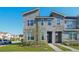 Contemporary townhome featuring stone accents, a well-manicured lawn, and modern architectural details on a sunny day at 1624 Tropical Palms Cir, Kissimmee, FL 34747