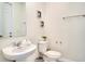 Well-lit half bathroom with a pedestal sink, modern toilet, and neutral decor at 1624 Tropical Palms Cir, Kissimmee, FL 34747