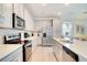 Modern kitchen featuring white cabinets, stainless steel appliances, quartz countertops and a large center island at 1624 Tropical Palms Cir, Kissimmee, FL 34747