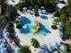 Aerial view of colorful splash pad and nearby lounge chairs with umbrellas in tropical setting at 1624 Tropical Palms Cir, Kissimmee, FL 34747