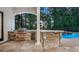 Outdoor kitchen featuring stone accents, built-in grill, and bar seating overlooking the pool area at 1906 Oakbrook Dr, Longwood, FL 32779