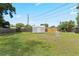 Well-maintained backyard with lush grass, a storage shed, and a charming stone accent piece at 207 Rose St, Auburndale, FL 33823