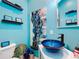 Stylish powder room features a unique blue glass bowl sink, modern decor, and turquoise walls at 2147 Whitfield Ln, Orlando, FL 32835