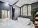 Luxurious bathroom featuring a soaking tub, glass shower, marble floors and arched windows at 2147 Whitfield Ln, Orlando, FL 32835