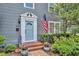 Close-up of the entry with an American flag, brick steps, potted plants, and decorative trim around the light blue door at 216 E Vanderbilt St, Orlando, FL 32804