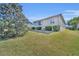 Well-maintained backyard featuring manicured lawn, mature trees, and tidy shrubbery at 2192 Kerwood Loop, The Villages, FL 32162