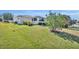 Expansive backyard with lush green lawn, mature trees, and a charming patio area at 2192 Kerwood Loop, The Villages, FL 32162