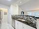 Modern kitchen sink with black countertop and white cabinets, showcasing the tile backsplash and stainless steel dishwasher at 232 Afton Sq # 201, Altamonte Springs, FL 32714