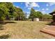View of the spacious backyard featuring green grass, mature trees, and a storage shed at 255 Katrina St, De Leon Springs, FL 32130