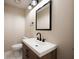 Modern bathroom with a wood vanity, white sink, black fixtures, and contemporary lighting and mirror at 2611 Albion Ave, Orlando, FL 32833
