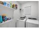 Laundry room features white appliances, shelving with cleaning supplies, and a window for natural light at 3065 Timber Hawk Cir, Ocoee, FL 34761