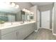 A modern bathroom featuring double sinks, white countertops, gray cabinets, and wood-look tile flooring, offering a stylish design at 3200 Town And Country Rd, Oviedo, FL 32766