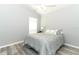 A light and airy bedroom featuring gray walls, wood-look floors, a ceiling fan, and a comfortable blue patterned bedspread at 3200 Town And Country Rd, Oviedo, FL 32766