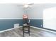 A light, open room with gray and dark blue walls, wood-look flooring, easel with colorful art, and a ceiling fan at 3200 Town And Country Rd, Oviedo, FL 32766