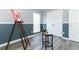 An open room with gray and dark blue walls, wood-look flooring, an easel with colorful art, and a ceiling fan at 3200 Town And Country Rd, Oviedo, FL 32766
