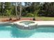 Inviting in-ground pool and attached spa, surrounded by landscaping and a black metal fence at 3200 Town And Country Rd, Oviedo, FL 32766