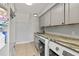 Bright laundry room with gray cabinets, a granite countertop, and modern washer and dryer units at 3535 Lake Sarah Dr, Orlando, FL 32804