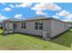 Back exterior view of the home featuring lush green grass, an AC unit, and dark roof at 439 Sarah Nicole Way, New Smyrna Beach, FL 32168