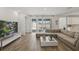 Comfortable living area with tan sectional, sliding glass doors, wood-look flooring, and modern decor at 4779 Cragmere Loop, Clermont, FL 34711