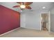 Carpeted bedroom with a maroon accent wall, ceiling fan, and access to another room at 5510 Siracusa Ln, Sanford, FL 32771