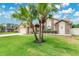 Landscaped front yard with mature palm trees and a welcoming entrance to the home at 5836 Goldenwood Dr, Orlando, FL 32817