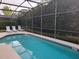 Relaxing screened-in pool with lounge chairs and privacy hedges for serene outdoor enjoyment at 643 Orista Dr, Davenport, FL 33897