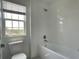 Bathroom featuring white tiled shower and tub, toilet, and window at 6712 Golden Eagle Blvd, Howey In The Hills, FL 34737