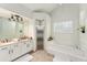 Well-lit bathroom with double vanities, a glass-enclosed shower, and a luxurious soaking tub at 7237 Edmund Ct, Mount Dora, FL 32757