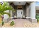 Inviting front porch with seating, decorative pillows and potted palm tree and beautiful curb appeal at 7237 Edmund Ct, Mount Dora, FL 32757