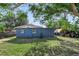 Backyard view of a blue home featuring a well-kept lawn and surrounding mature trees at 7727 Arezzo Ave, Orlando, FL 32819