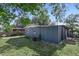 Backyard view of a home with blue siding and a well-maintained lawn surrounded by trees at 7727 Arezzo Ave, Orlando, FL 32819