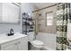 Neutral-tiled bathroom featuring a toilet, sink with a mirror, and shower with a decorative curtain at 7727 Arezzo Ave, Orlando, FL 32819