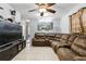 Inviting living room featuring tile floors, ceiling fan and a comfortable oversized brown sectional couch at 7727 Arezzo Ave, Orlando, FL 32819