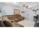 Inviting living room featuring tile floors, ceiling fan and a comfortable oversized brown sectional couch at 7727 Arezzo Ave, Orlando, FL 32819