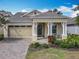 Charming single-story home featuring a manicured lawn, front porch, and an attached two-car garage at 7748 Four Seasons Blvd, Kissimmee, FL 34747