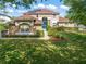 Charming two-story home featuring a well-manicured lawn, lush landscaping, solar panels, and a vibrant blue front door at 7867 Horse Ferry Rd, Orlando, FL 32835