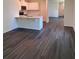 Modern kitchen featuring white cabinets, an island, and stylish wood-look flooring throughout the open-concept living space at 976 Commons Way, Port Orange, FL 32129