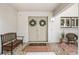Close-up of condo entrance with double doors, welcome mat, bench, and charming decorative details at 1000 Winderley Pl # 140, Maitland, FL 32751