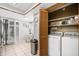 Bright laundry room featuring a full sized washer and dryer, shelving, and ample natural light through the shuttered door at 1000 Winderley Pl # 140, Maitland, FL 32751