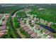 Aerial view of homes surrounding pond, nestled among mature trees in a neighborhood with a city skyline in distance at 141 Campanello Ct, Daytona Beach, FL 32117